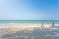 Happy older brother and little sister playing and surfing on white sand beach, light blue sky backgrounds. Summer season. Sunny