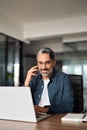 Happy older business man talking on phone working on laptop in office. Vertical Royalty Free Stock Photo