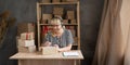 Happy older businesswoman in headset talking on conference call while placing order in warehouse, mature aged woman Royalty Free Stock Photo