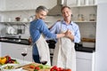 Happy older couple dancing in kitchen preparing healthy meal, having fun. Royalty Free Stock Photo