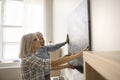 Happy older couple hanging picture on wall at home