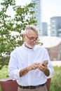 Smiling senior business man holding mobile phone using cell in city park. Royalty Free Stock Photo