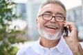 Happy older business man talking on cell phone making call in city outside. Royalty Free Stock Photo