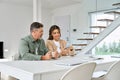 Happy older mature family couple using cell phone sitting at home table. Royalty Free Stock Photo