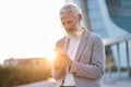 Happy older professional business man holding phone using cellphone outdoor. Royalty Free Stock Photo