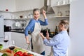 Happy older middle aged couple having fun dancing and cooking together at home. Royalty Free Stock Photo