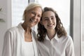 Happy older mom and cheerful adult daughter woman standing close