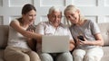 Happy older parents with adult daughter using electronic devices Royalty Free Stock Photo