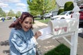 Happy older senior citizen woman smiles as she removes a blank white envelope from a white mailbox Royalty Free Stock Photo