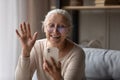 Happy older smartphone user woman waving hand hello at screen Royalty Free Stock Photo