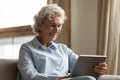 Happy older woman holding digital tablet, reading electronic book. Royalty Free Stock Photo