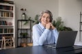 Happy older woman sit at workplace desk looking into distance Royalty Free Stock Photo