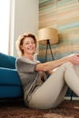 Happy older woman sitting on floor of cozy apartment Royalty Free Stock Photo