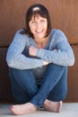 Happy older woman sitting on floor and smiling Royalty Free Stock Photo