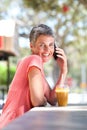 Happy older woman sitting outside with drink and talking on cellphone Royalty Free Stock Photo