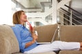 Happy older woman sitting on sofa with laptop and credit card Royalty Free Stock Photo