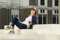 Happy older woman sitting on steps in city listening to music Royalty Free Stock Photo