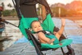 Happy one year old baby in a compact pram for traveling on the pier Royalty Free Stock Photo