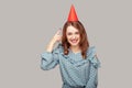 Happy optimistic carefree girl ruffle blouse pointing at funny party hat on head, looking at camera smiling