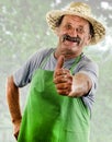 Happy organic farmer with a green apron shows his upraised thumb