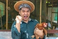 Happy organic Middle aged farmer hold chicken in his arms in front of hen house in countryside. Farmer is glad for success. Of chi