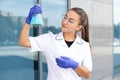 Happy oriental chemist girl in a white coat, rubber gloves and goggles holding a chemical flask