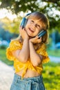 Happy child girl in wireless headphones choosing, listening music in smartphone dancing outdoors Royalty Free Stock Photo