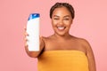 Happy Oversized Black Lady Showing Shampoo Bottle Over Pink Background