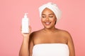 Happy Oversized Black Woman Holding Cosmetic Bottle Over Pink Background