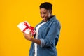 Happy Oversized Black Woman Holding Gift Standing Over Yellow Background