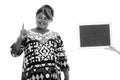 Happy overweight African woman thinking while pointing finger up with blank blackboard Royalty Free Stock Photo