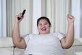 Happy overweight Asian woman clenched her fists while holding a remote control