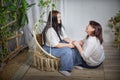 Happy Overweight family with mother and daughter in room on a wicker swing. Middle aged woman and teenager girl having Royalty Free Stock Photo