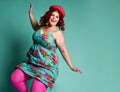 Happy overweight fat chubby woman in funny hat and colorful clothes dances on popular mint