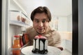 Happy overweight man taking cake out of refrigerator in kitchen, view from inside Royalty Free Stock Photo