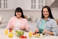 Happy overweight women having healthy meal together at table in kitchen Royalty Free Stock Photo