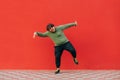 Happy overweight young man in casual clothes dancing on red background and looking at camera with smiling face. Isolated Royalty Free Stock Photo