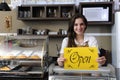 Happy owner of a cafe showing open sign