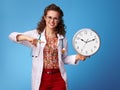 Happy paediatrician doctor pointing at clock on blue