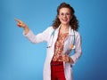 Happy paediatrist woman pointing at something on blue