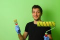 Happy painter decorator holding a brush and roller in his hands on a background of freshly painted Royalty Free Stock Photo