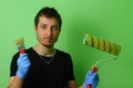 Happy painter decorator holding a brush and roller in his hands on a background of freshly painted green Royalty Free Stock Photo