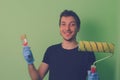 Painter decorator holding a brush and roller in his hands on a background of freshly painted green wall Royalty Free Stock Photo