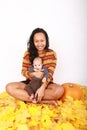 Happy mother and baby boy sitting on maple leaves by pumpkin Royalty Free Stock Photo