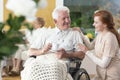 Happy paralyzed senior man in a wheelchair drinking tea and a ca Royalty Free Stock Photo