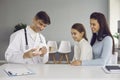 Pediatric dentist or oral hygienist teaching little girl to brush teeth properly