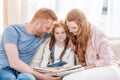 Happy parents with adorable little daughter sitting together and reading book Royalty Free Stock Photo