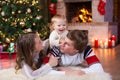 Happy parents and child have a fun near Christmas tree at home. Father, mother and son celebrating New Year together Royalty Free Stock Photo