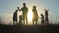 Happy parents with children waving hands at sunset.