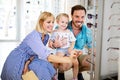 Happy mother and father choosing eyeglasses frame with their daughter in optical store